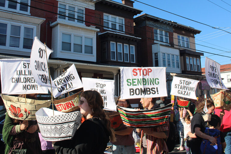 People hold various signs as they march in the 25th annual Peoplehood Parade in West Philadelphia