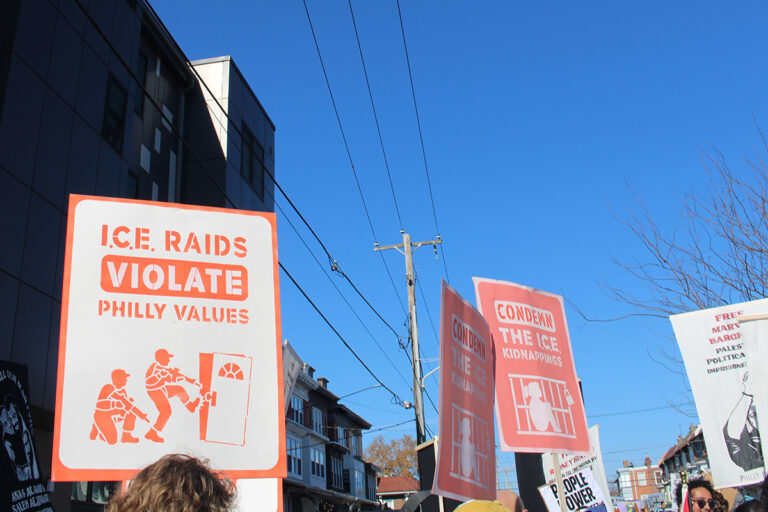 People hold up various signs in the 25th annual Peoplehood Parade in West Philadelphia