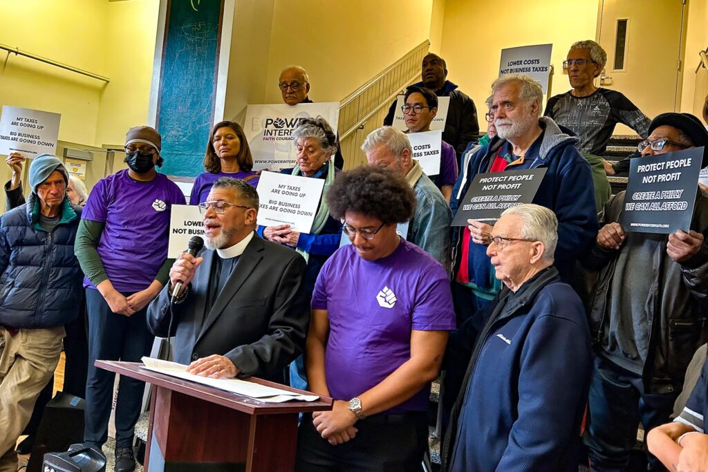 power-a-moselle-2025-11-10-1 Rev. Gregory Edwards speaking at the podium surrounded by other people