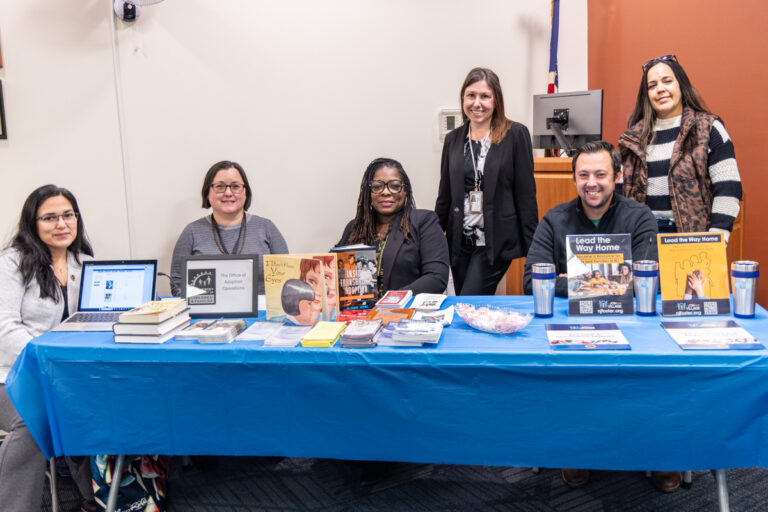 Vendors pose for a photo behind their information table at the resource fair