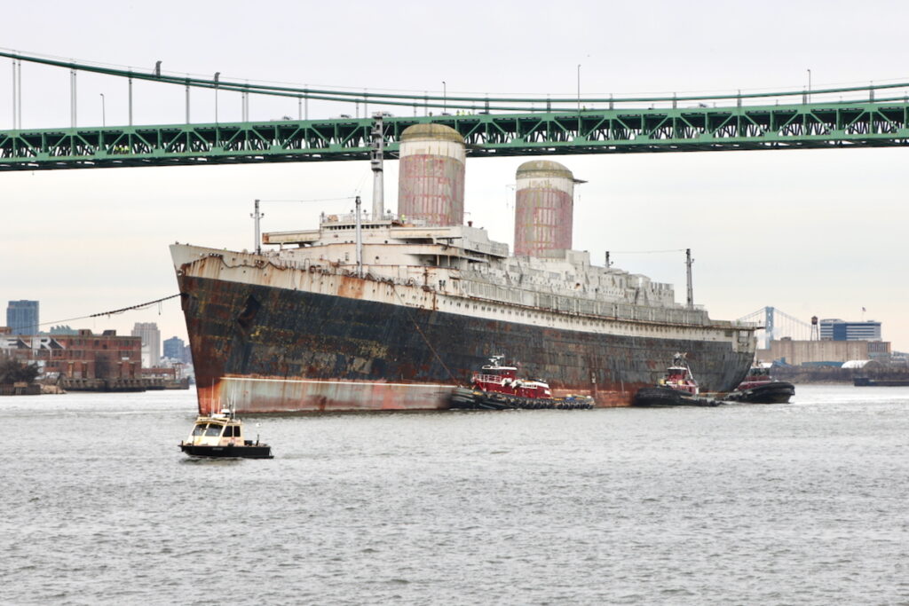 The S.S. United States passes under the Walt Whitman Bridge on Feb. 19, 2025, on its journey to Florida. (Emma Lee/WHYY)