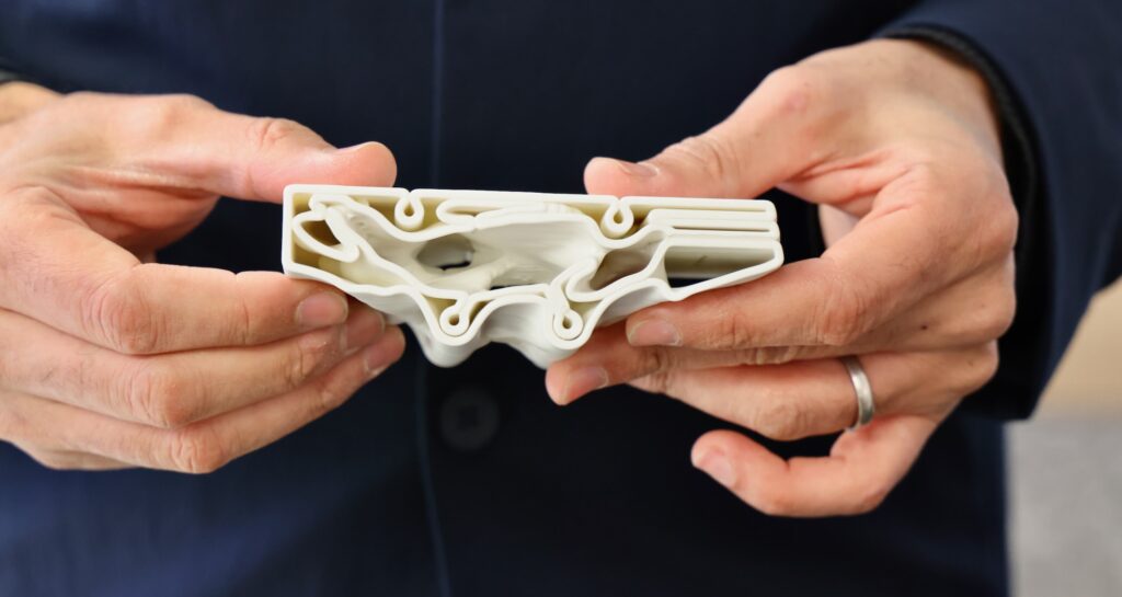 Masoud Akbarzadeh, director of the Polyhedral Structures Laboratory at the University of Pennsylvania, holds a model cross section that shows the complex structure of the 3D printed concrete sections