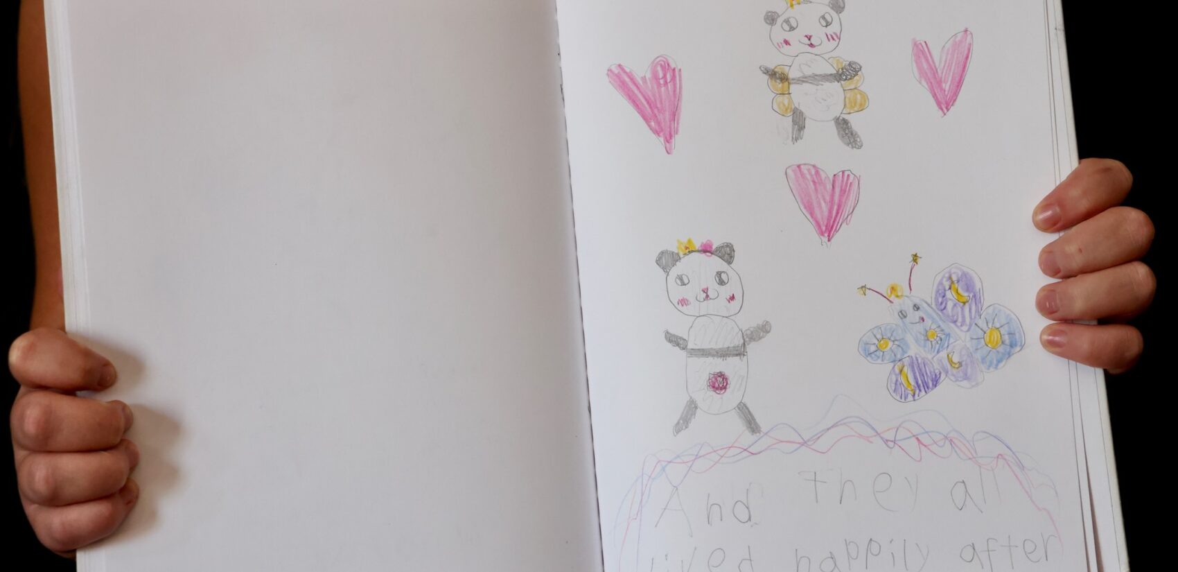 A book shows a children's drawings of a panda, a butterfly and a pandafly