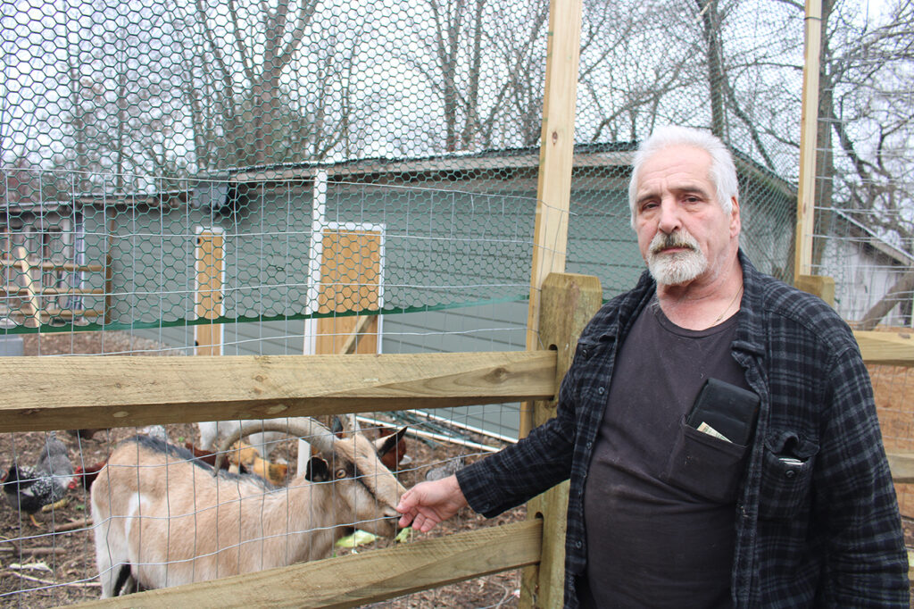 ken-schumann-bam-bam-goat A man stands next to a goat in a pen