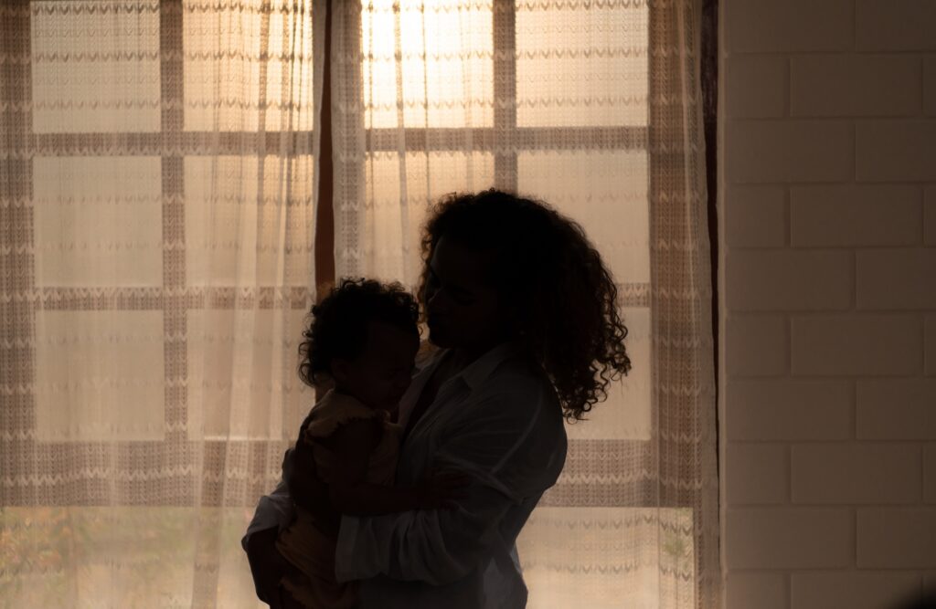 Mother and children enjoy the morning sunlight shining through the bedroom window in the house.