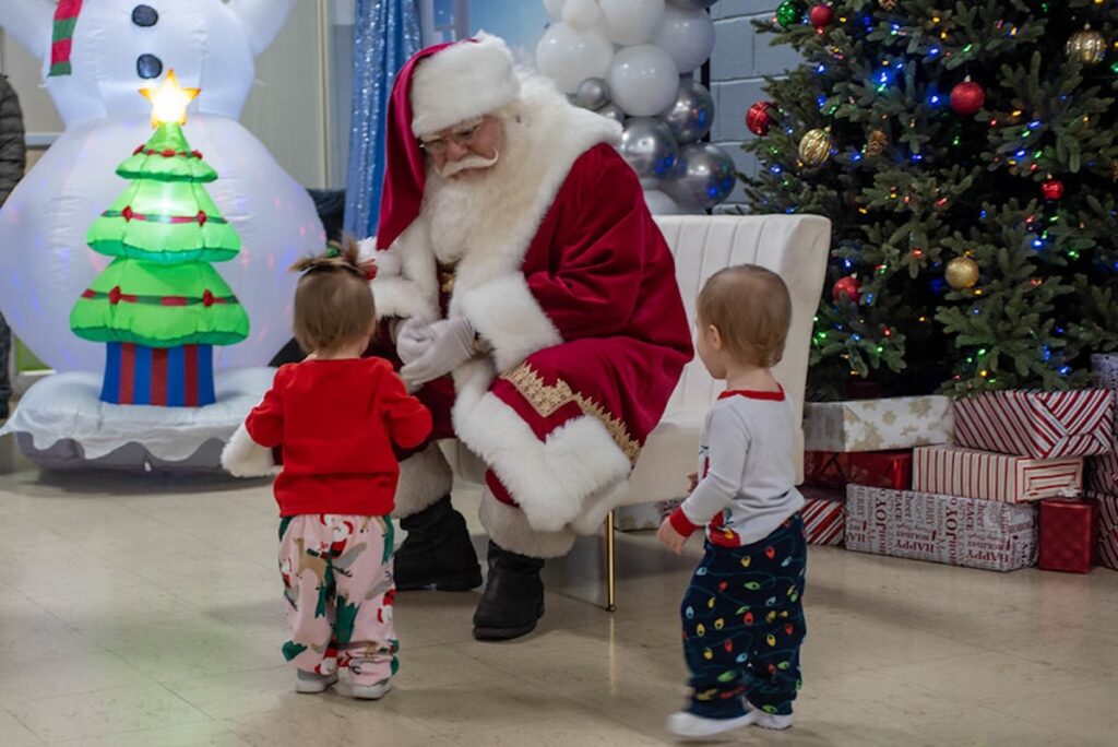 one-simple-wish-2025-12-23-WISH 2 A person dressed as Santa greets two very young children