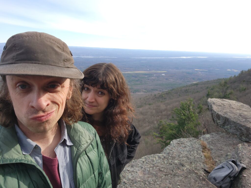 walnut_brain-2025-12-13-2 A selfie photo of Steve Heise and Alina Josan standing on a large hill overlooking a wide landscape