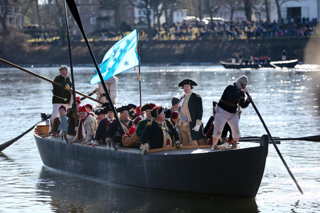 People in a boat reenact General George Washington and his troops crossing the Delaware River during the American Revolution