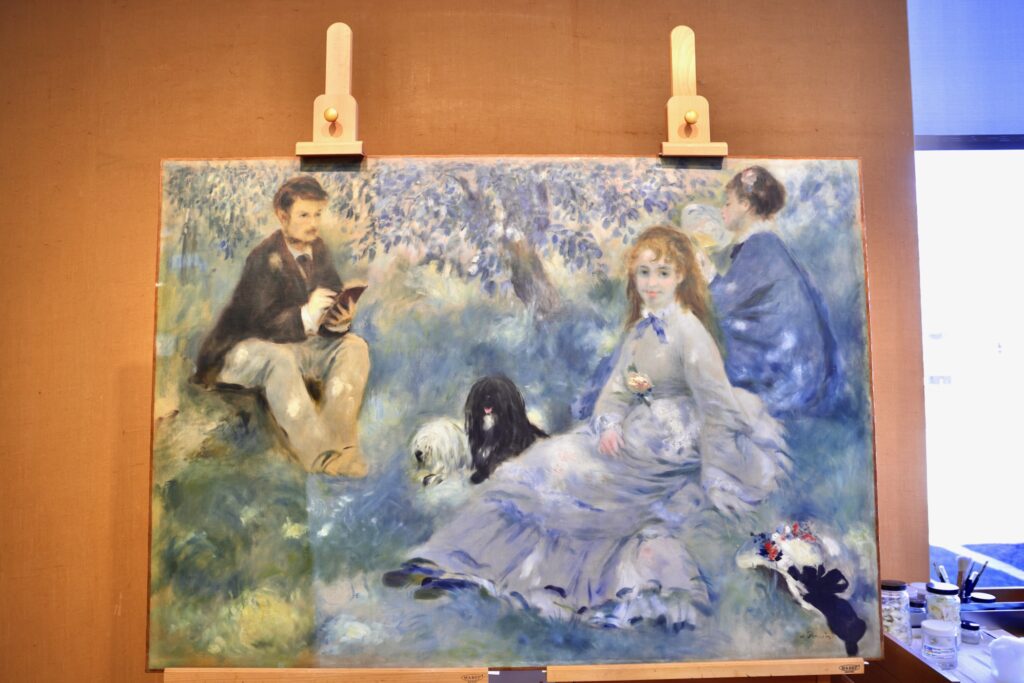 Pierre-Auguste Renoir's 1875 painting, ''The Henriot Family'' is undergoing conservation at The Barnes Foundation. A yellowed coat of resin is being removed, revealing a brighter, bluer painting long hidden. (Emma Lee/WHYY)