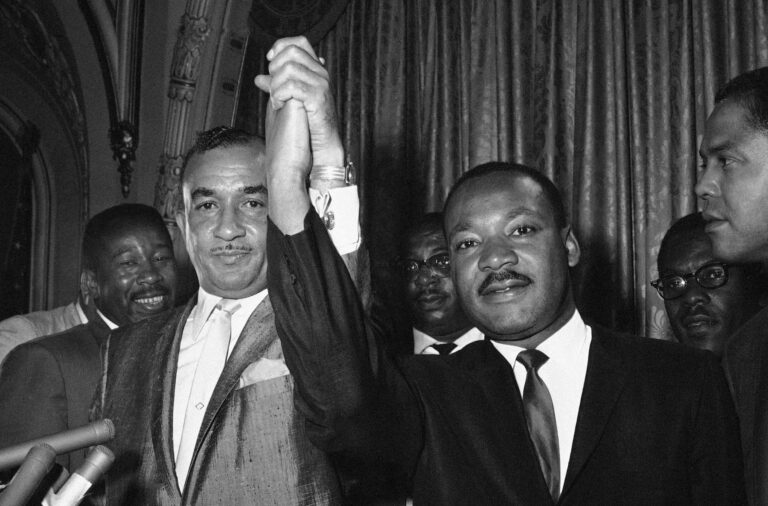 Cecil Moore, left, NAACP, leader in Philadelphia, and Dr. Martin Luther King, integration leader, raises their hands in a gesture of unity in Philadelphia August 2, 1965, where Dr. King started a two-day visit. Moore earlier had requested Dr. King not to come here but they said the controversy was “a misunderstanding.” Dr. King hailed picketing at the all-white Girard College by the NAACP served to “dramatize the problem.” African American  are attempting to break provisions of the college’s founder calling for only white students admitted. (AP Photo/Bill Ingraham )
