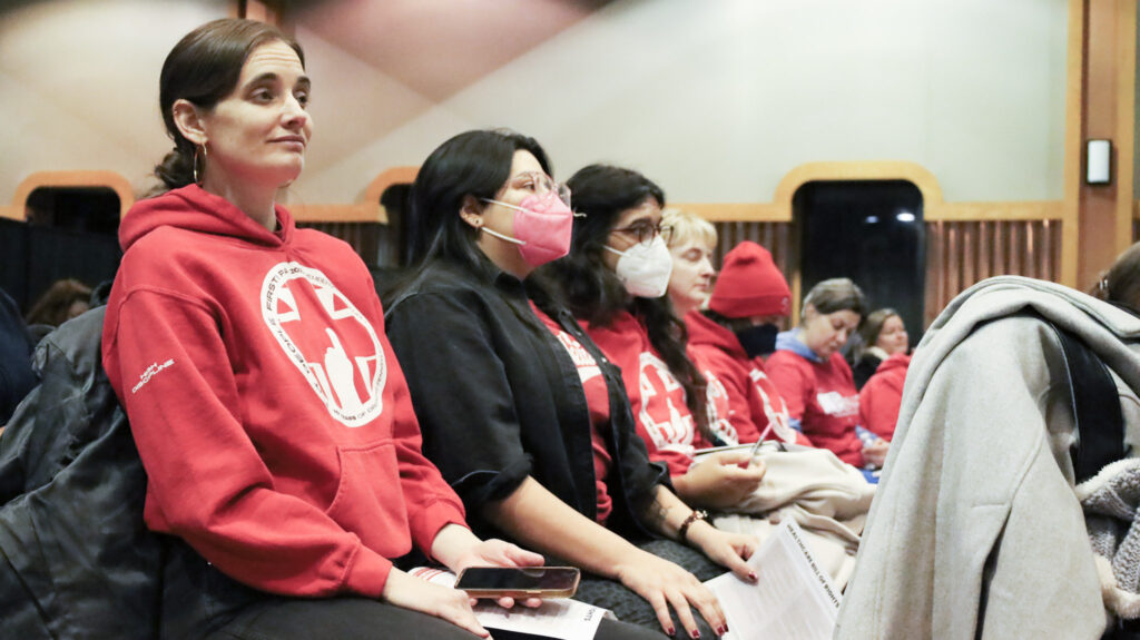 PASNAP forum 3 Health care workers and advocates sit in a forum, most wearing the same red sweater