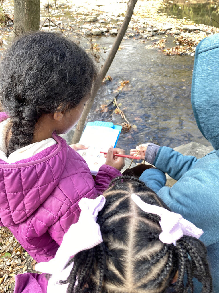 Children look at a notebook outside