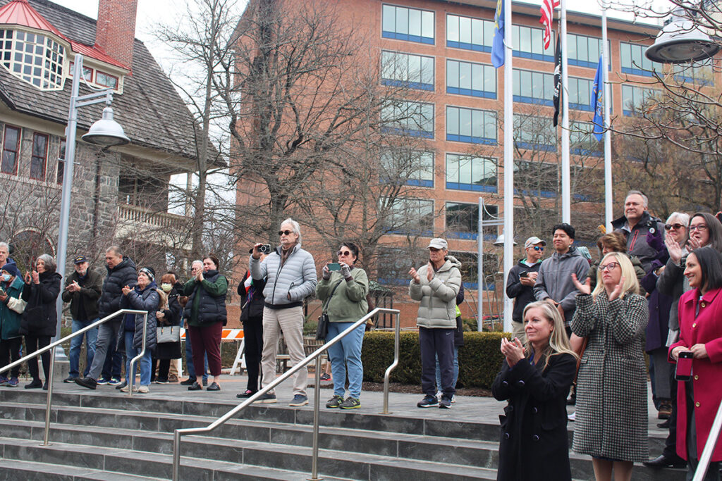 A small crowd of spectators in Bucks County applauds while standing on outside steps