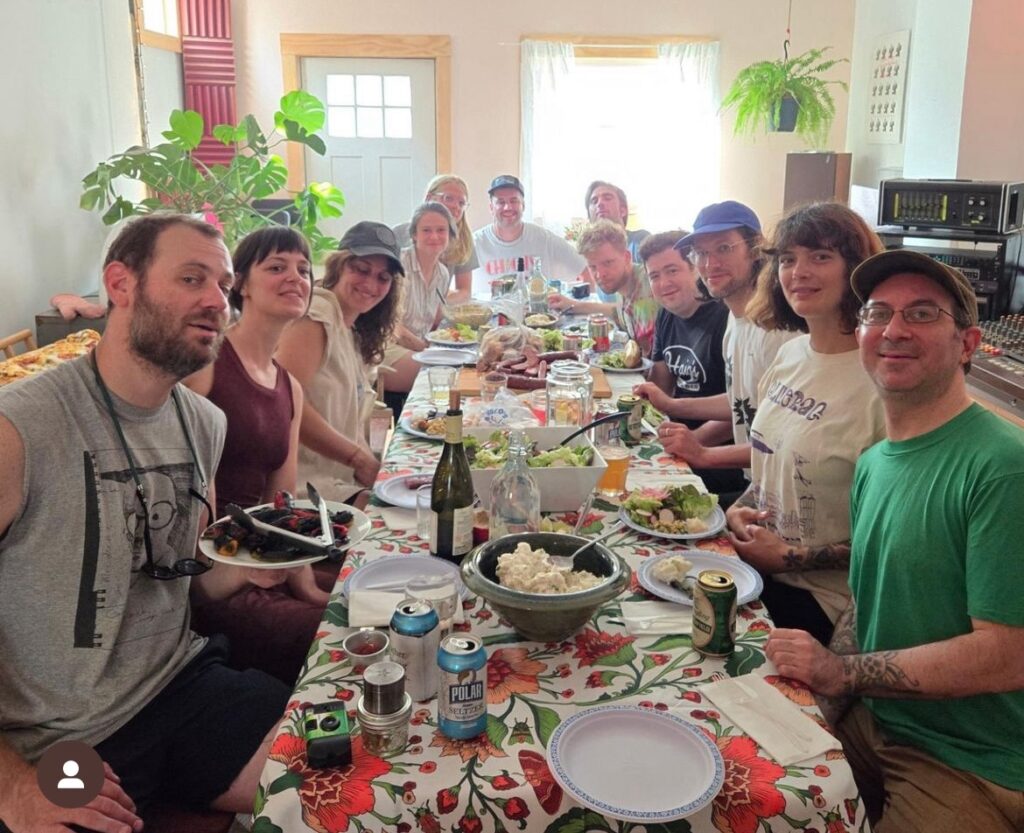 A large group of people sitting inside at a large table with a lot of food.