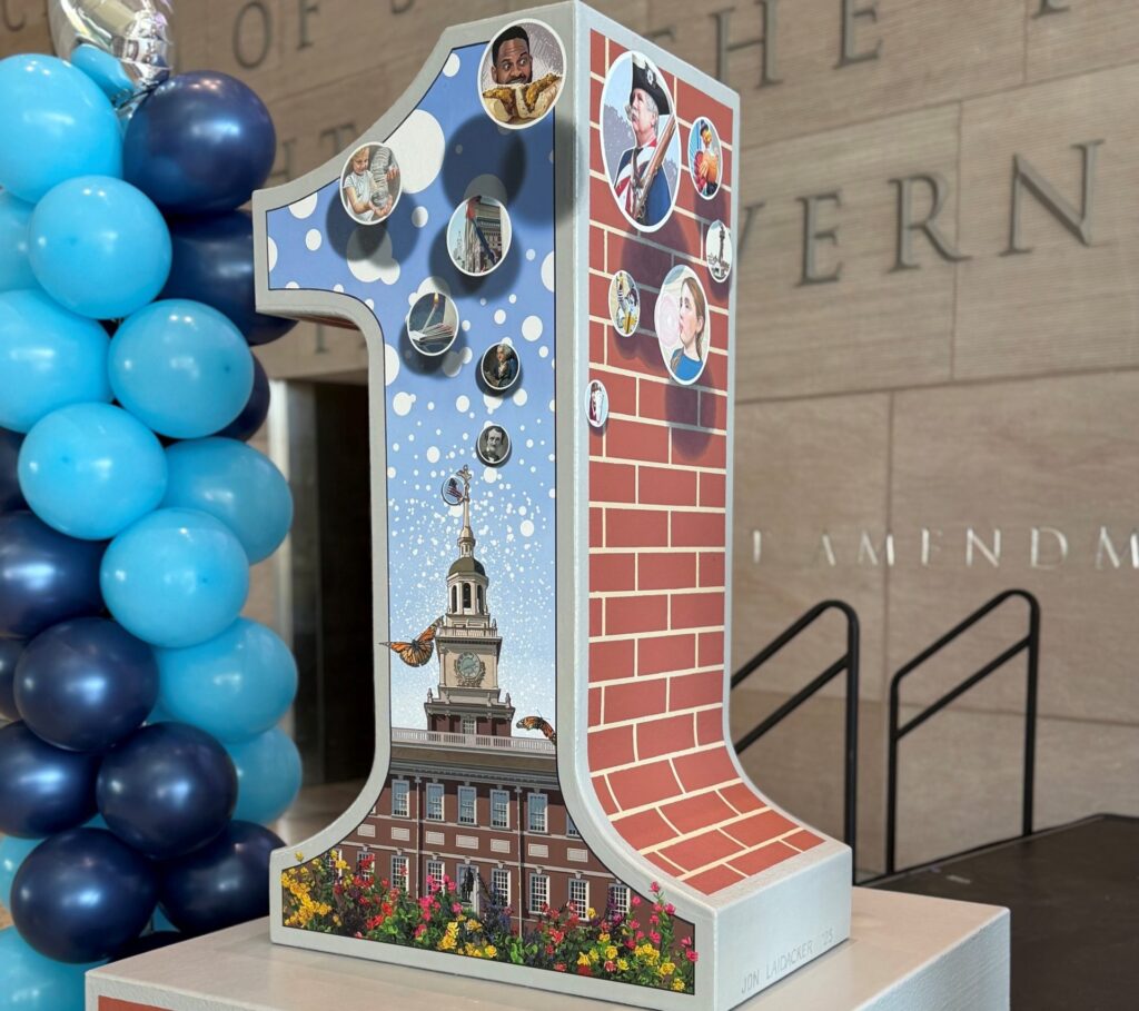 A large sculpture of the numeral 1, decorated with various Philly artifacts