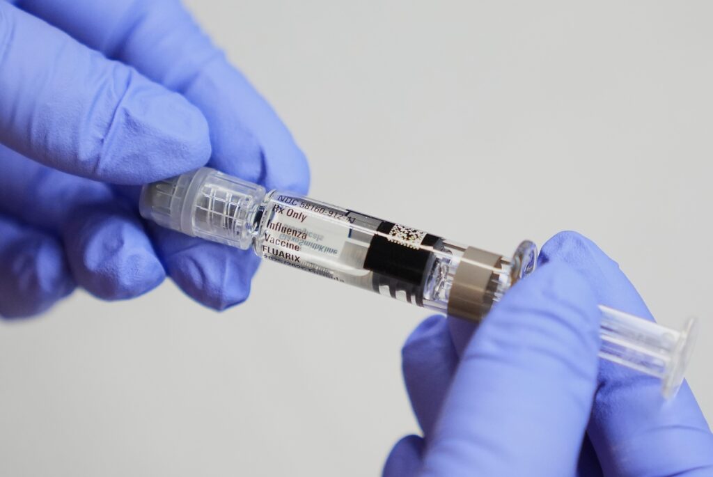Flu-What to Know A certified medical assistant holds a syringe for a flu vaccine