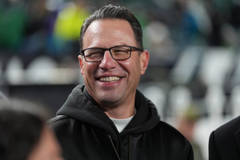 Josh Shapiro smiling as he stands on the sidelines during a football game