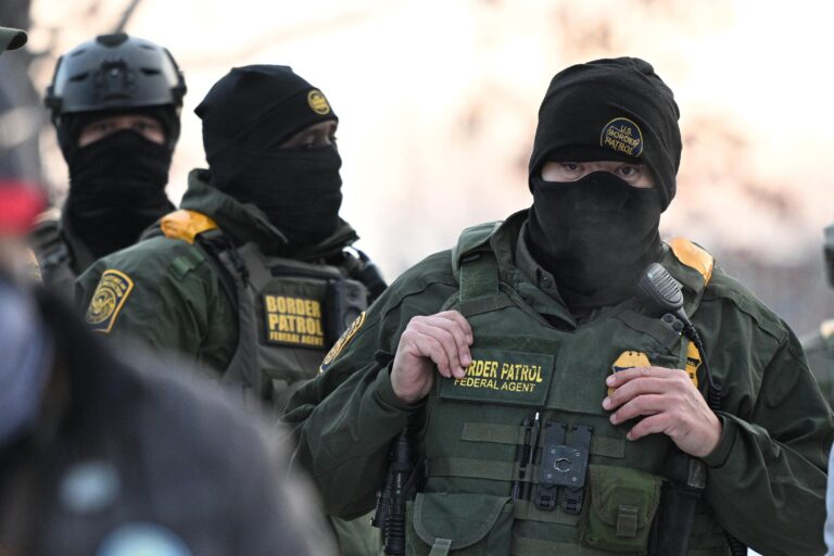 Federal agents look on as protesters gather outside the Bishop Henry Whipple Federal Building, Thursday, Jan. 8, 2026, in Minneapolis, Minn. (AP Photo/Tom Baker)