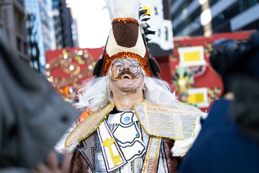 A patriotic mummer wearing copies of the Constitution performs