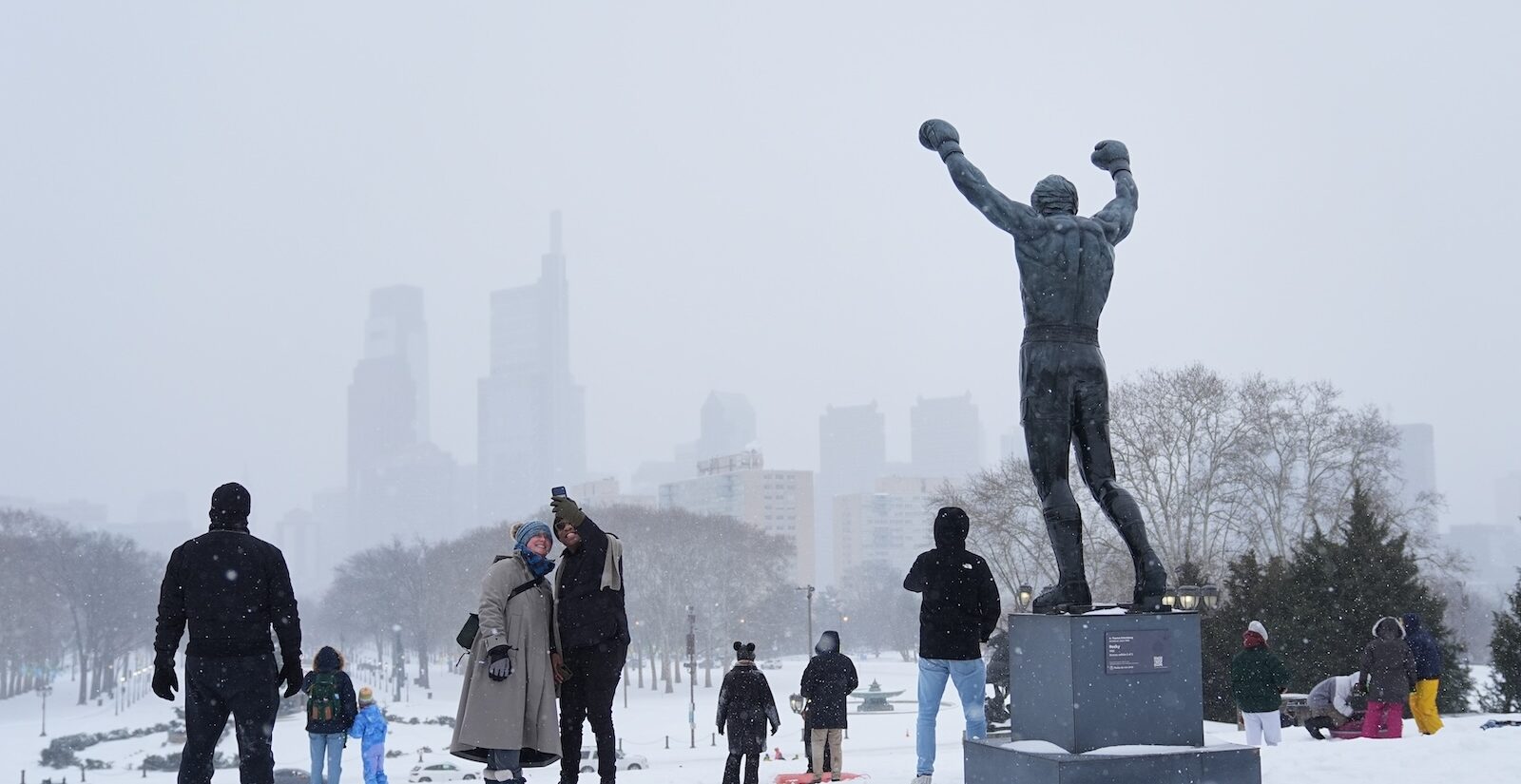 People gather at Philadelphia Art Museum steps by the Rocky statue during a winter storm in Philadelphia, Sunday, Jan. 25, 2026.