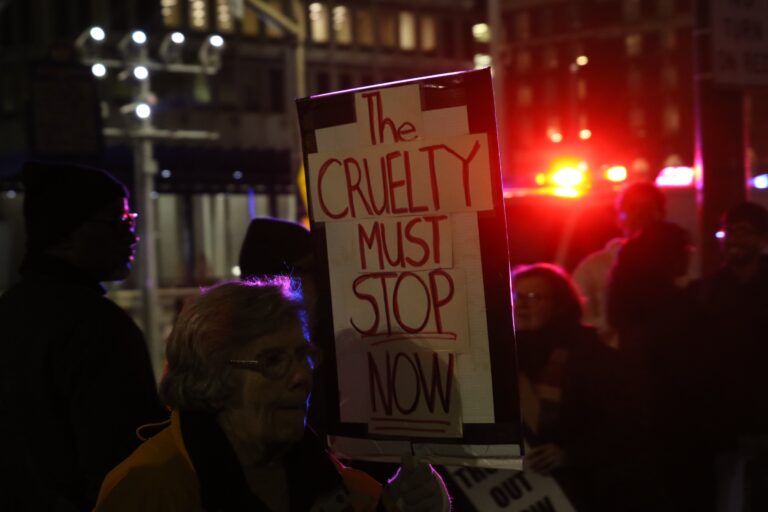 Protesters holding up signs as they gather in City Hall following the ICE shooting in Minneapolis