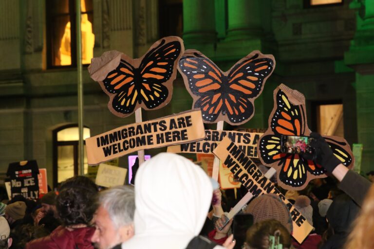 Protesters holding up signs as they gather in City Hall following the ICE shooting in Minneapolis