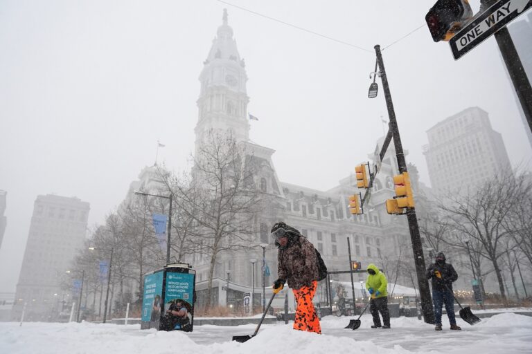 Walkers shovel sidewalks during a winter storm in Philadelphia, Sunday, Jan. 25, 2026.
