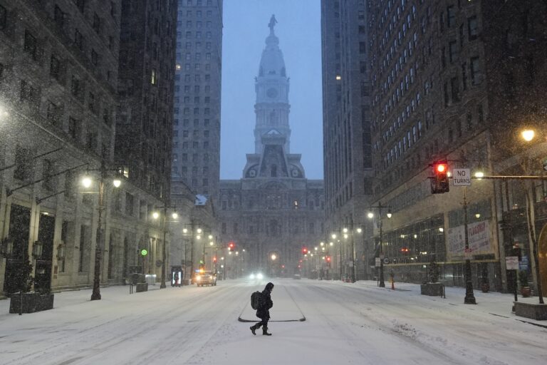 A person walks across a street during a winter storm in Philadelphia, Sunday, Jan. 25, 2026.