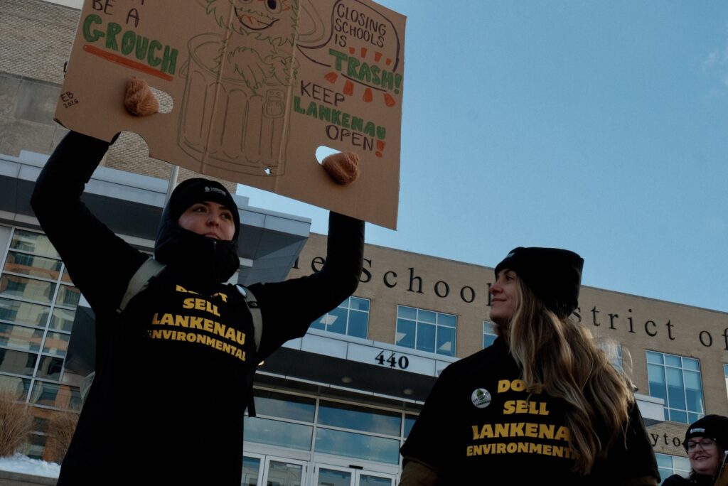 philly-school-closure-rally-b-bennett-2026-01-29-2 Two people holding up signs at a rally in front of the Philadelphia School District