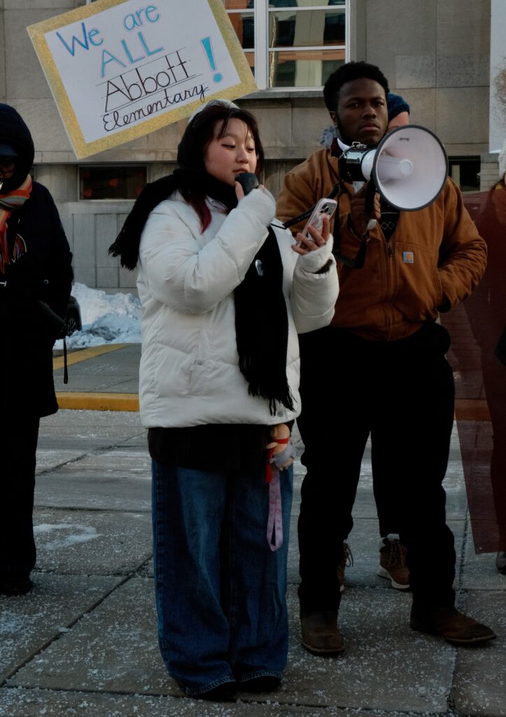 Ella Nguyen speaking into a megaphone at the rally in front of the School Board building