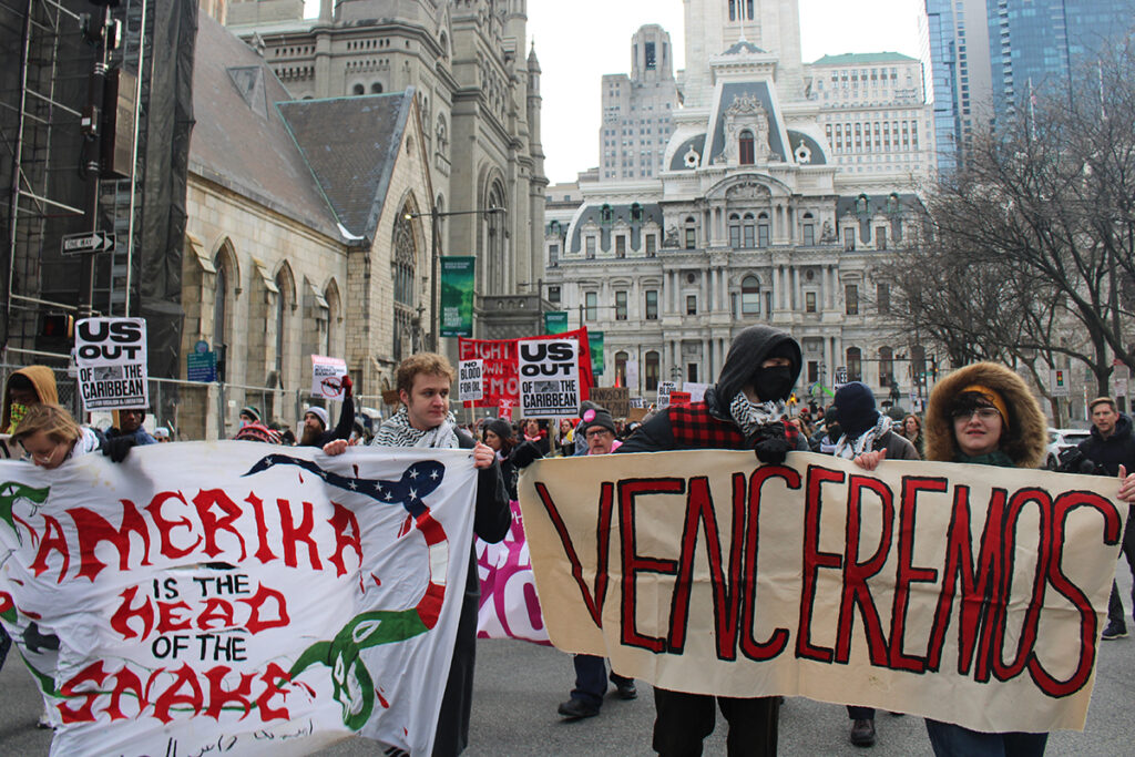 protest-4 People march in Philadelphia holding signs protesting the U.S. military intervention in Venezuela