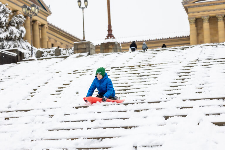 Christian Coretese, 11, rides a sled down the art museum steps after a snowstorm in Philadelphia on February 23, 2026.