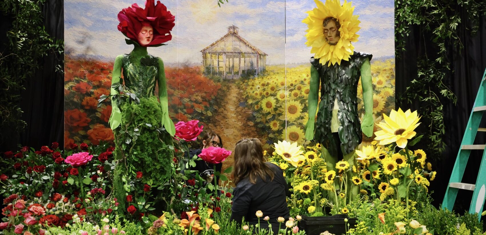 two faces are seen in a cutout with a backdrop of flowers at the flower show