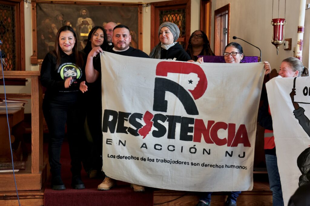 People holding up a large banner that says Resistencia En Acción NJ