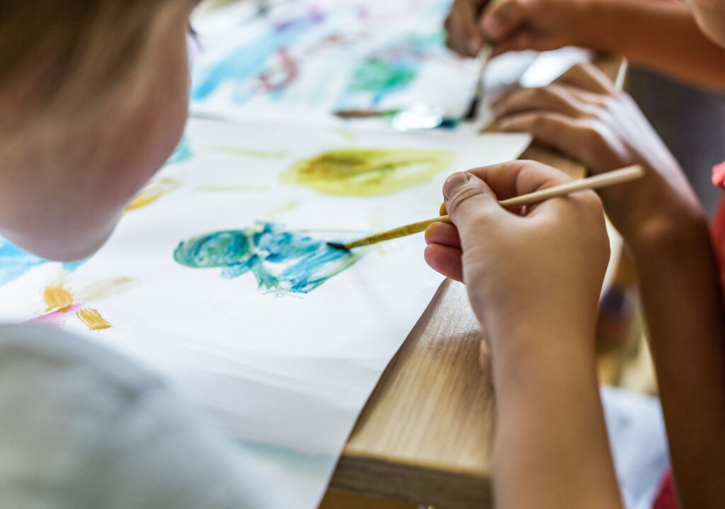 Art class at elementary school! Close up of elementary student using watercolors for painting on art class in the classroom.