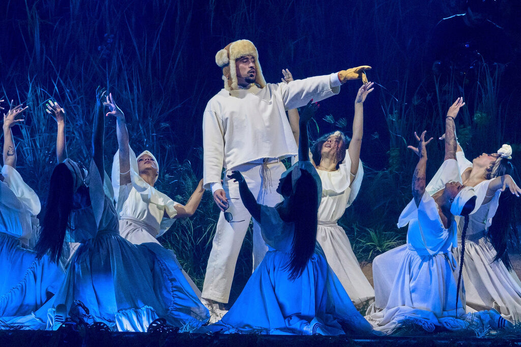 Puerto Rico Bad Bunny Lawsuit Artist Bad Bunny performs on stage, pointing to something in the distance while dancers surround him