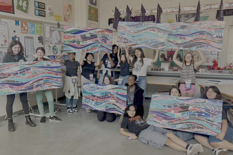 multiple students hold artwork