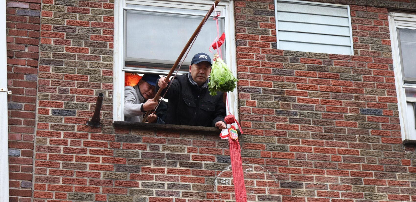 two people hold a fishing rod out of a window