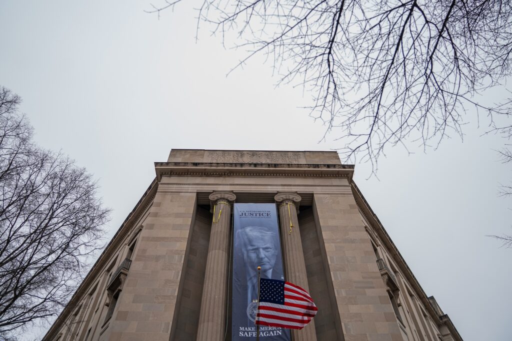 Trump Justice Department A large banner with Trump's face hangs on the side of a building