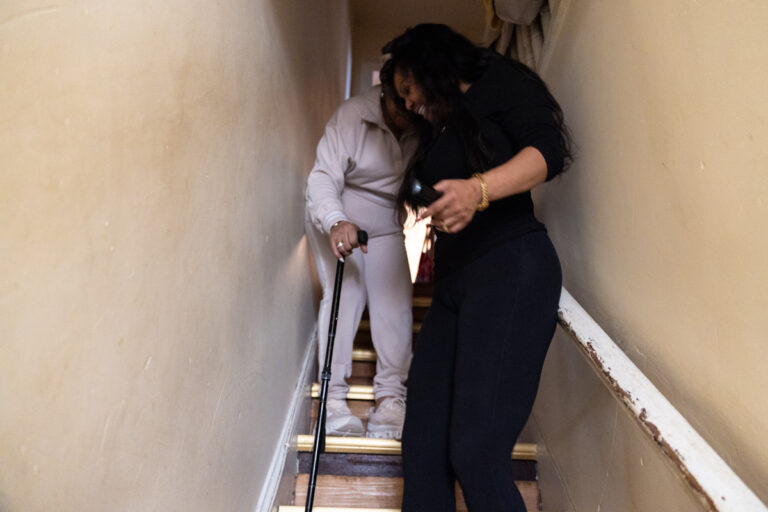 Tamara Baptiste walkiing Jacqueline Percell down the stairs