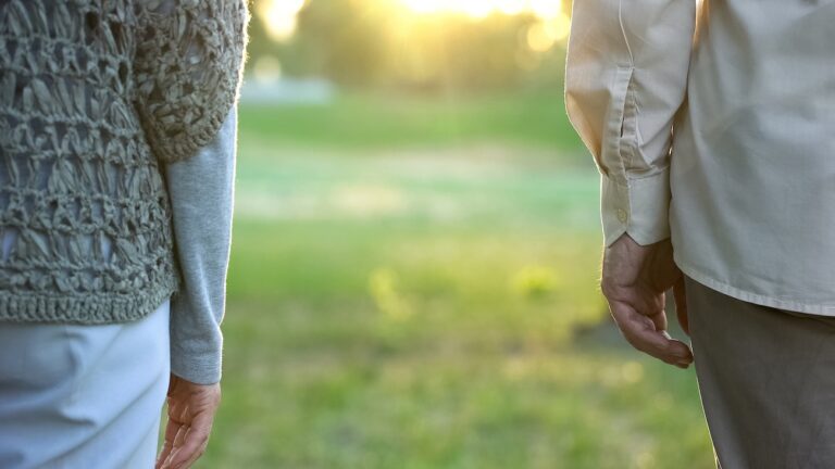 Old couple looking into future, standing apart in park indifference and break-up