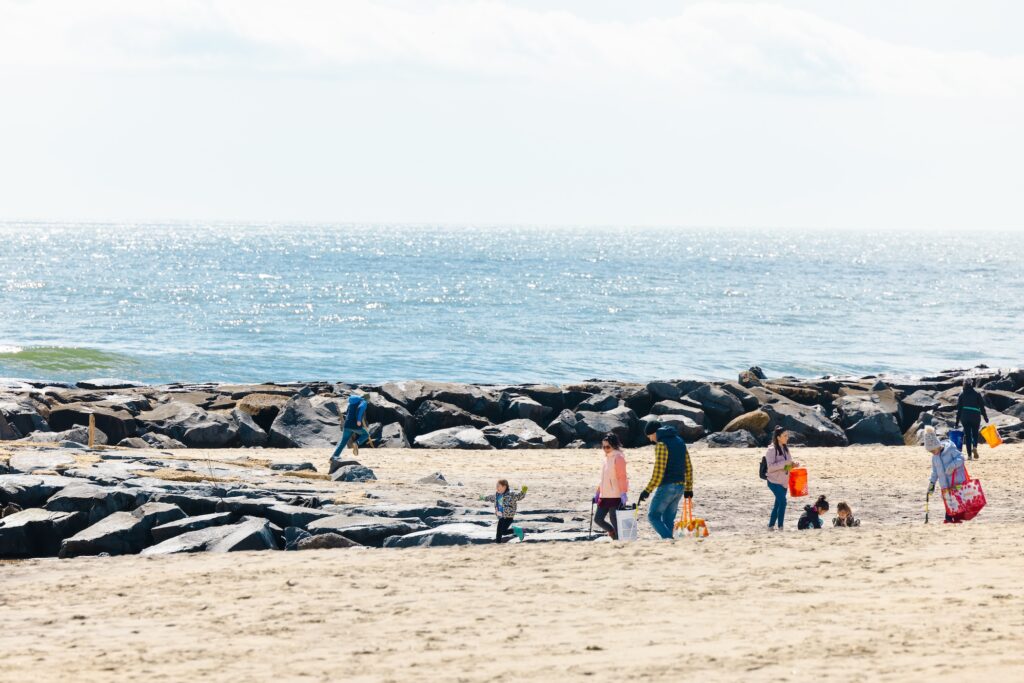 People walking along the beach picking up trash.