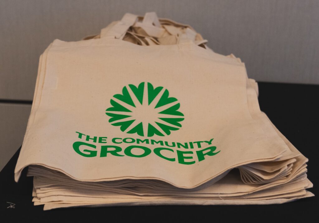 A stack of reusable bags with the Community Grocer logo on them