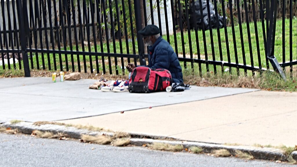 delaware-sidewalk-sitting-2026 A man sits on a sidewalk