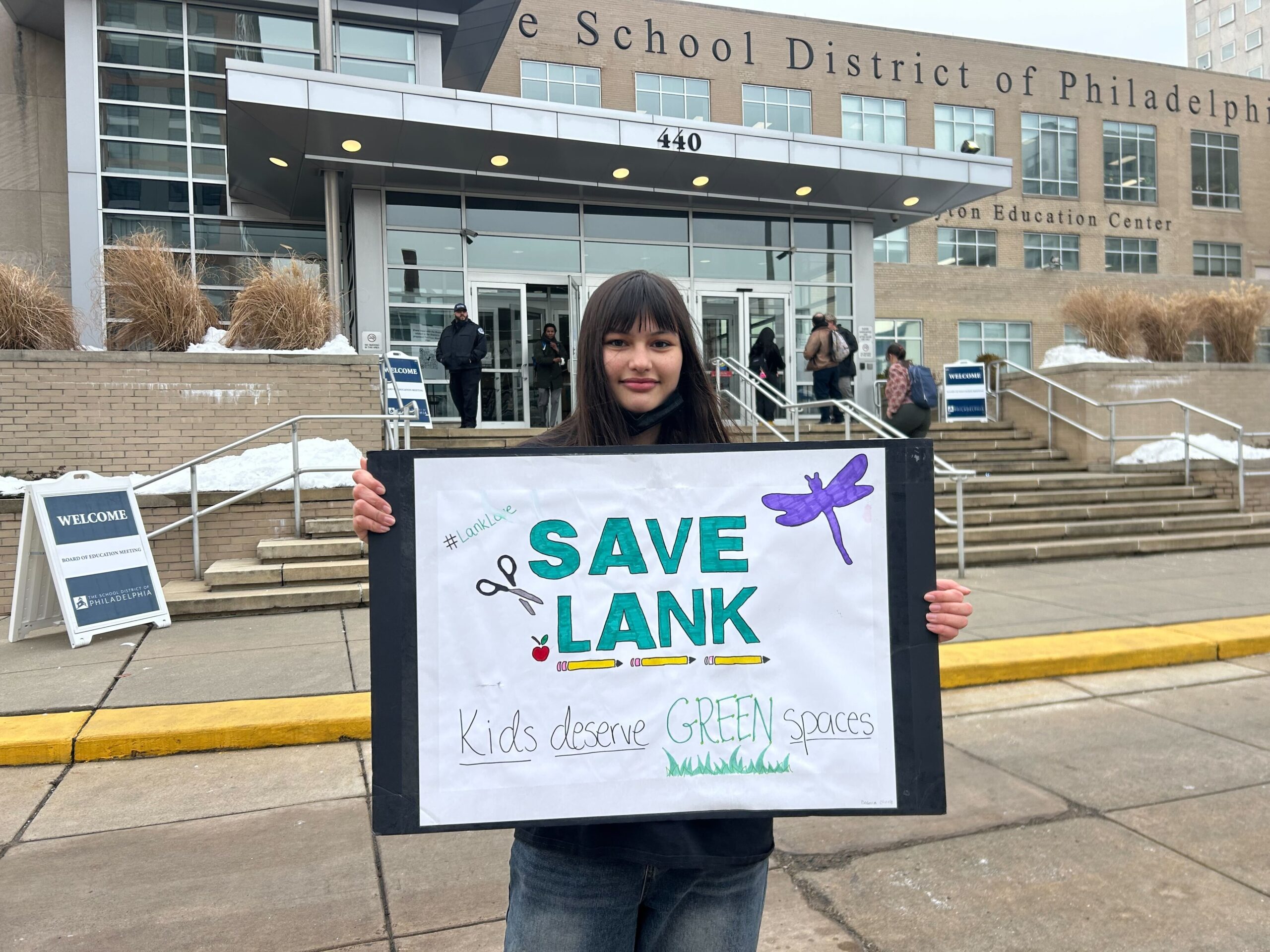 Alana Rothman holds a protest sign reading SAVE LANK Kids deserve GREEN spaces