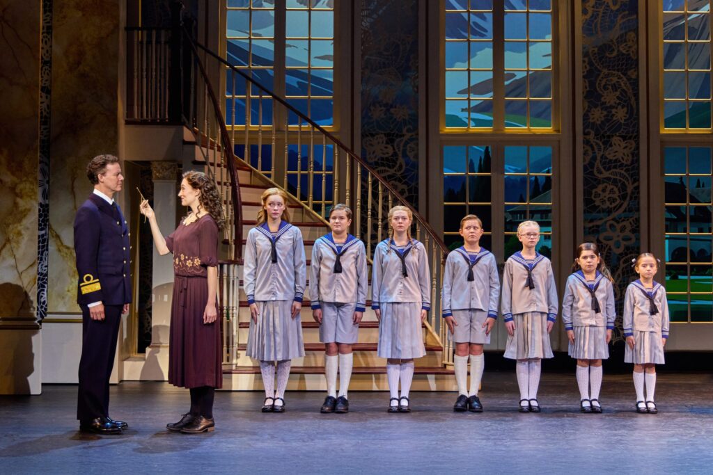 sound-of-music-bp-032726 Kevin Earley (Captain Georg von Trapp) and Cayleigh Capaldi (Maria Rainer) with the von Trapp Children