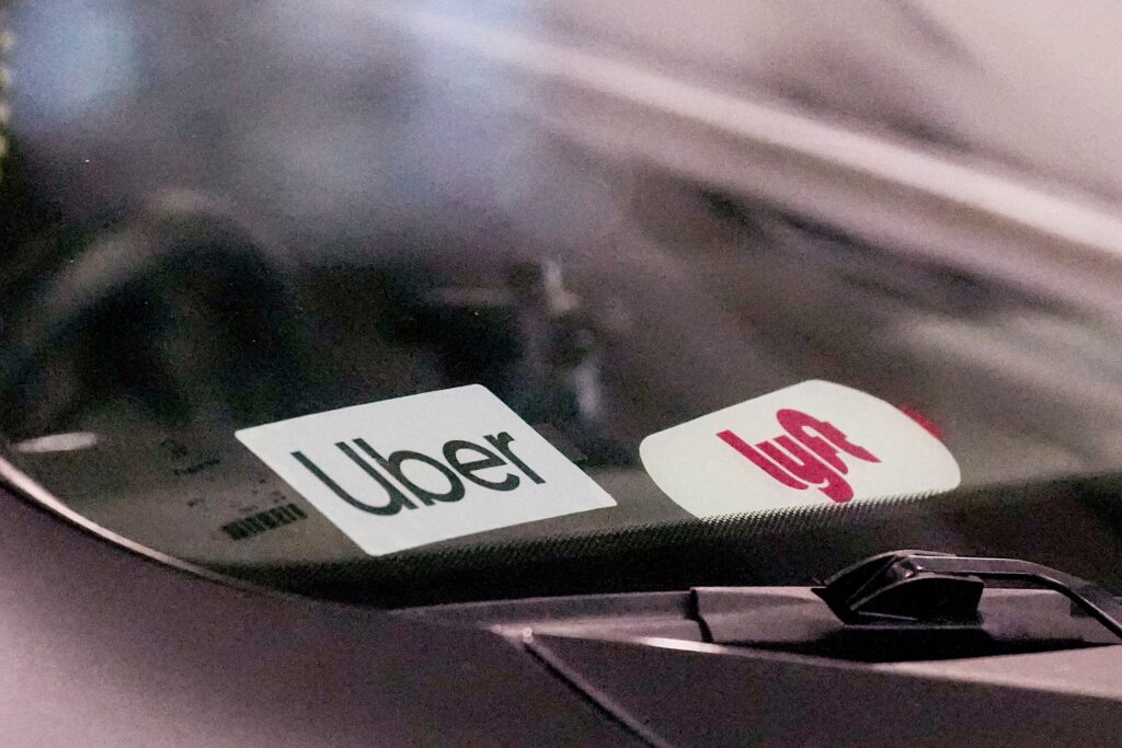 uber-lyft-file-ap Uber and Lyft stickers are seen on a rideshare vehicle