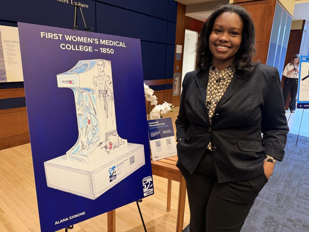 womens-medical-college-bp-031026 Artist Alana Sxmone stands next to a poster