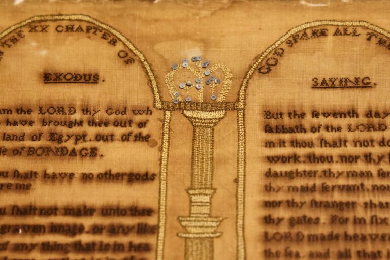 A sampler stitched by Rebecca Hendricks features the Ten Commandments and a crown