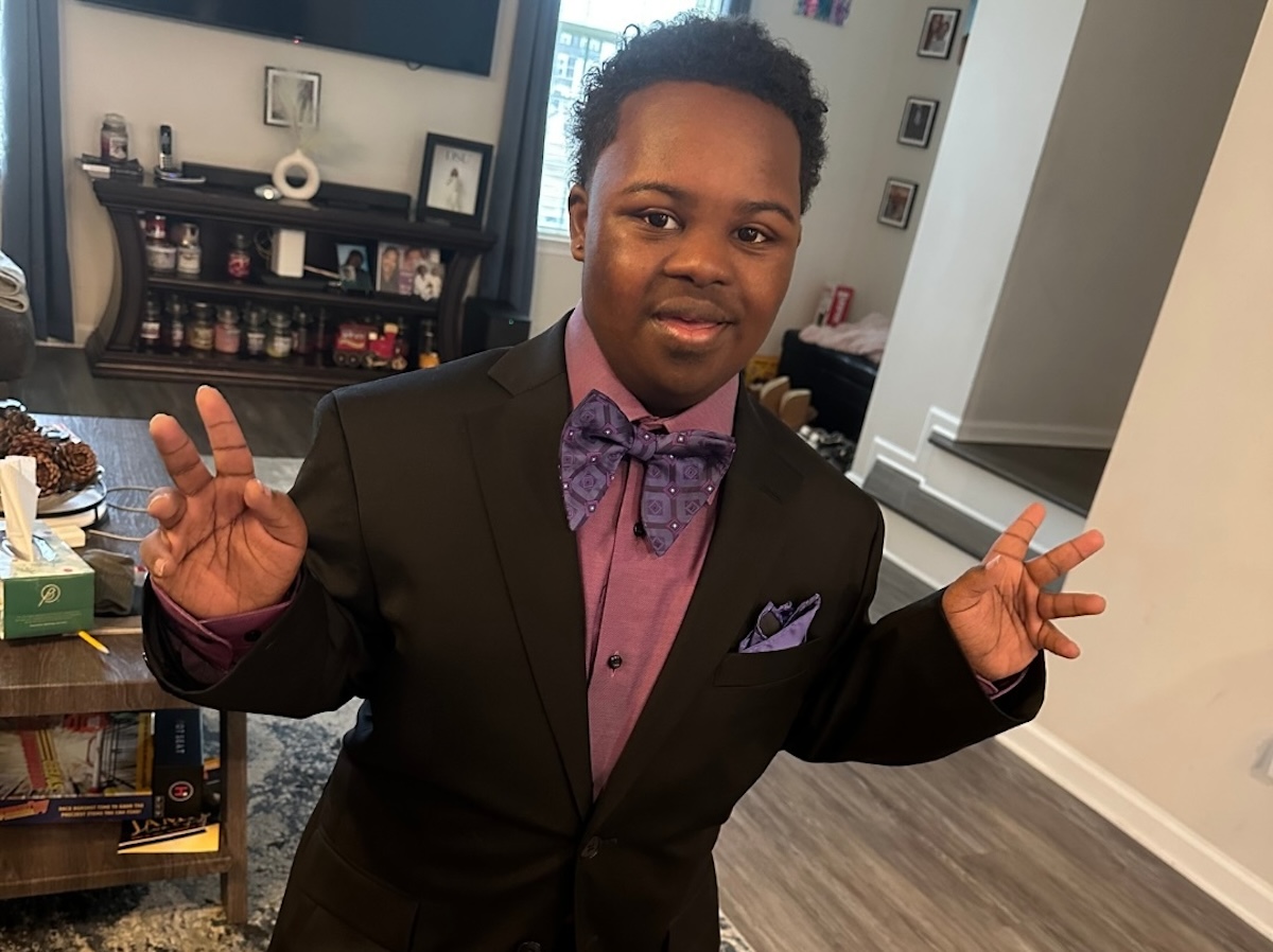 Bryan poses for a photo in his home dressed in a suit with a bowtie.